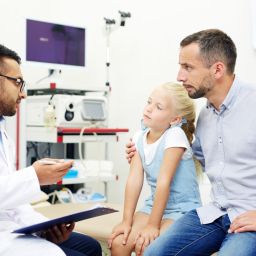 Pediatric clinician discussing immunization information with a parent and child during a counseling visit.