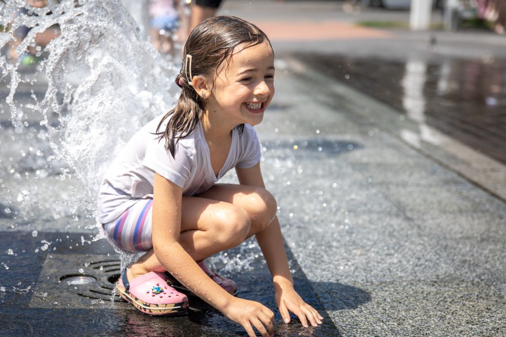 little girl playing in water during summer