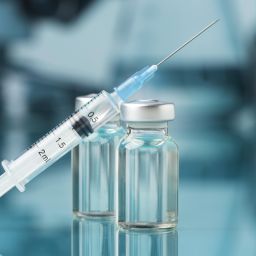 Syringe and vaccine vials in a medical setting, representing vaccine administration, immunization safety, and healthcare best practices.